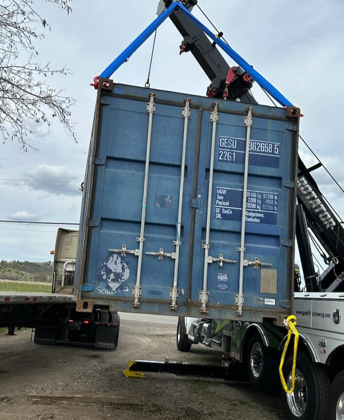 1. A truck lifting a container onto a flatbed. 2. A flatbed truck loading a container. 3. A container being lifted onto a flatbed truck.